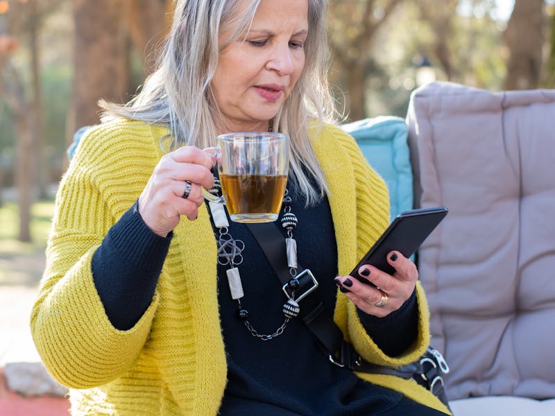 Person mit Smartphone am Tisch, entspannt
